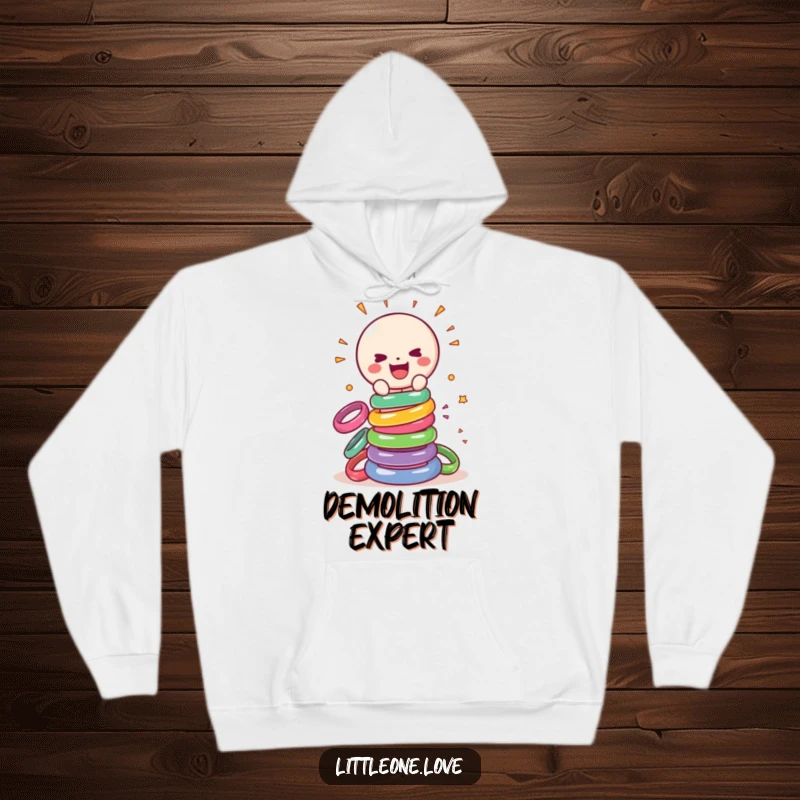 Funny hoodie depicting a happy, sentient baby rattle gleefully destroying a stack of colorful rings, a playful and cozy design.